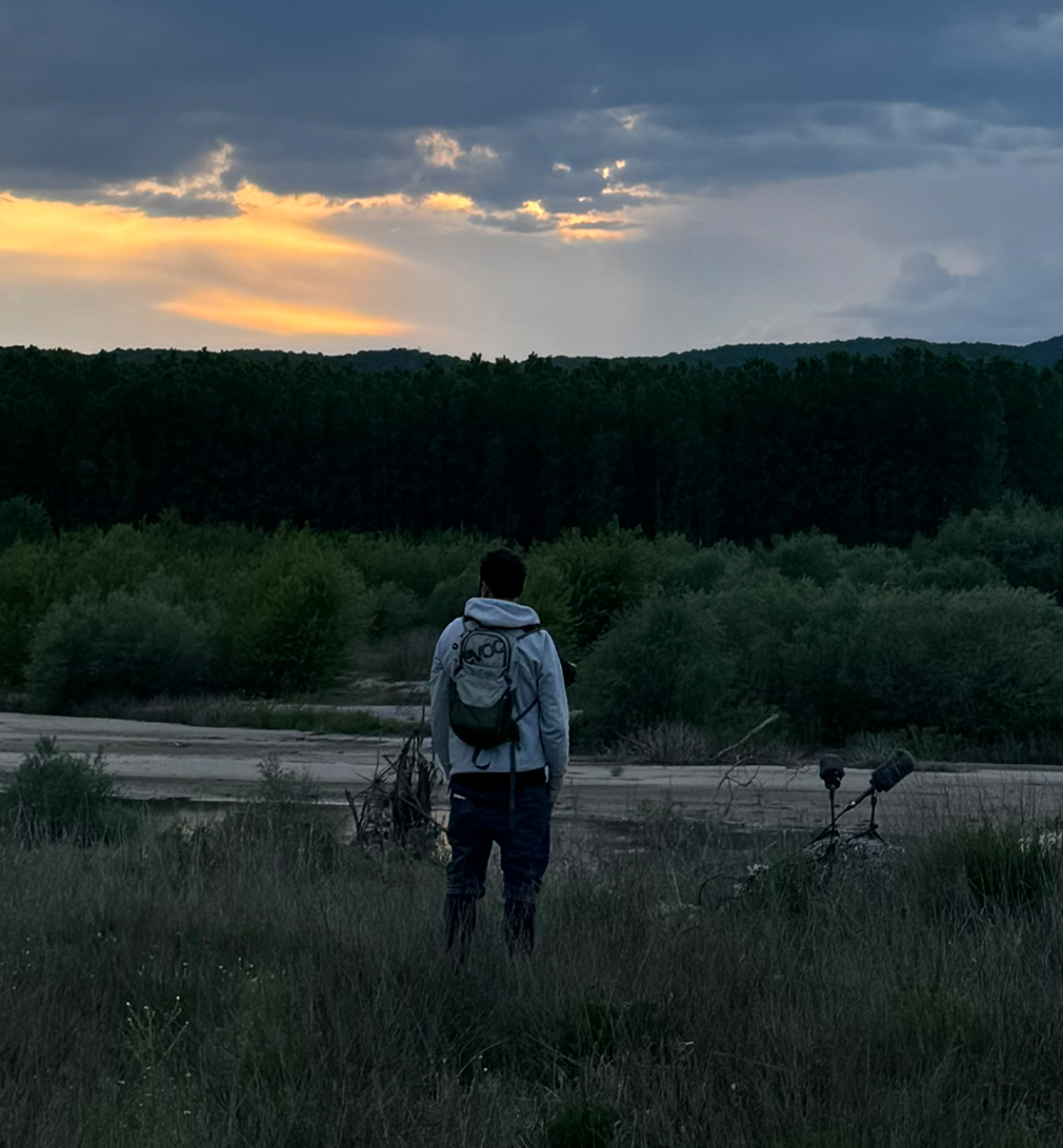 Simeon standing outdoors recording nature with professional audio equipment